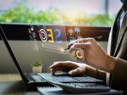 Business person's hands on computer with a colorful SEO image reflecting off a computer screen